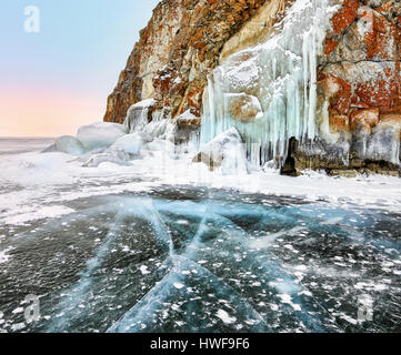 Fissures sur glace près de Baikal cape et de glaçons de splash sur glace rock côtières. Le lac Baïkal. L'île Olkhon Banque D'Images