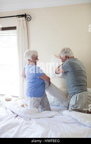 Senior couple having pillow fight sur le lit dans la chambre Banque D'Images