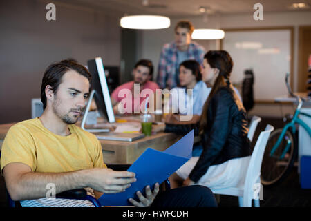 L'homme handicapé physique concentrée sur la lecture d'un fichier en fauteuil roulant in office Banque D'Images