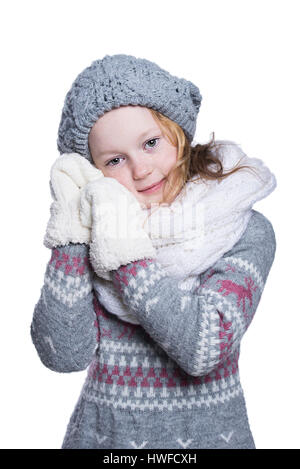 Happy cute kid posant dans le studio isolé sur fond blanc. Porter des vêtements d'hiver. Pull en laine tricotée, écharpe, chapeau et mitaines Banque D'Images