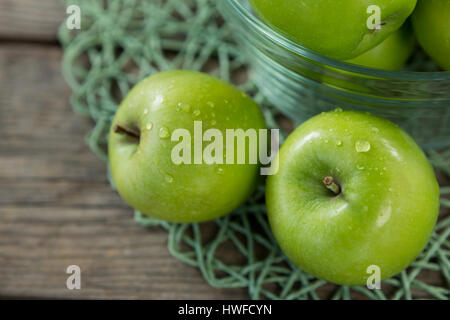 Close-up de pommes vertes avec des gouttelettes d'eau dans un bol sur bol en bois Banque D'Images