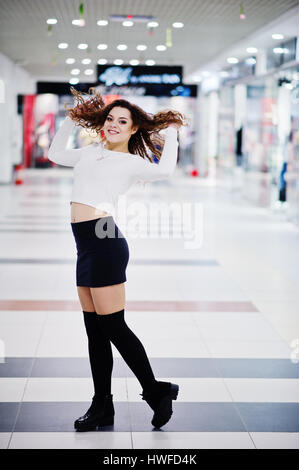 Jeune fille modèle curly posés sur mini jupe au grand centre commercial. Banque D'Images