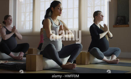 Femme enceinte assise en tailleur et de méditer dans le yoga class Banque D'Images