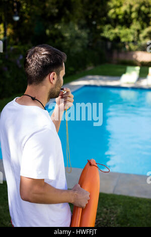 Lifeguard soufflant sifflent à la piscine sur une journée ensoleillée Banque D'Images