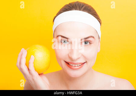 Jolie fille joyeuse avec un sourire à pleines dents pamplemousse sur fond jaune Banque D'Images