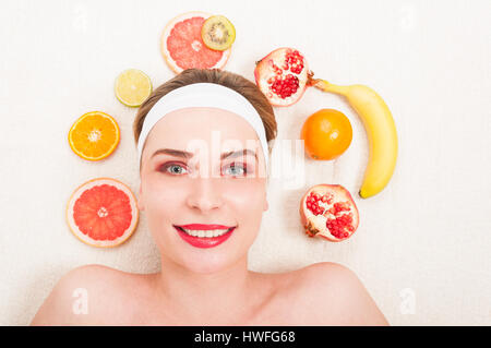 Jolie jeune femme avec un masque de fruits au spa beauté smiling gaiement tout en vous relaxant Banque D'Images