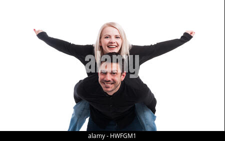 Young man giving piggyback ride à la femme qui se tient avec les bras tendus sur fond blanc Banque D'Images