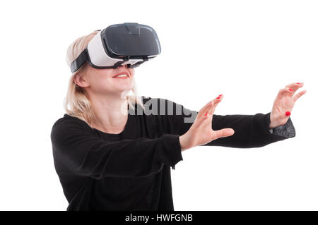 Jolie femme portant des lunettes de réalité virtuelle et attraper quelque chose d'invisible sur fond blanc Banque D'Images