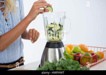 Smoothie aux légumes préparation femme against white background Banque D'Images