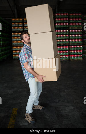 Side view of man carrying cardboard boxes in warehouse Banque D'Images