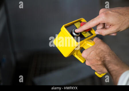 Les mains coupées de travailleur masculin à l'aide de l'outil jaune en usine Banque D'Images