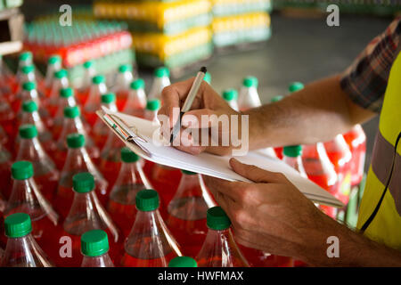 Section intermédiaire de travailleur homme notant sur les produits dans l'usine de jus Banque D'Images