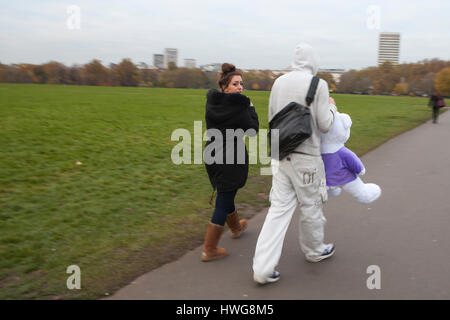 Londres, ANGLETERRE - 12 Décembre 2016 Un homme dans un costume de sport et d'une capuche porte un gros ours polaire. La jeune fille regarde par-dessus son épaule. Ils sont de retour avec un Ch Banque D'Images