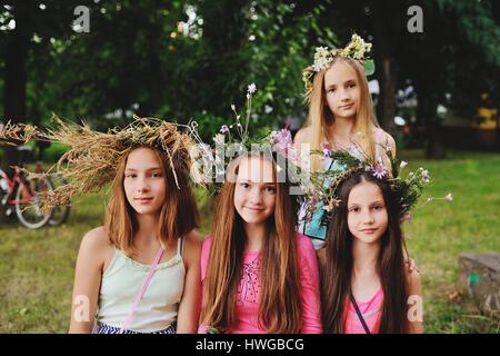 Quatre filles à leurs couronnes de fleurs sauvages dans le contexte de la nature Banque D'Images