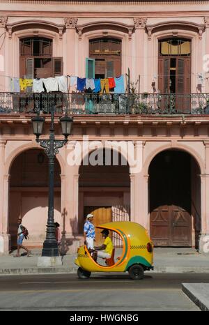 Cuba, La Havane, Paseo de Marti, coco taxi jaune en passant en face de bâtiments néoclassiques Banque D'Images