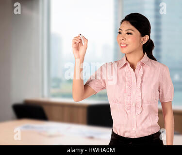 Asian woman écrit quelque chose sur le bureau Banque D'Images