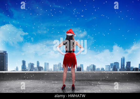 Asian woman wearing santa claus costume, debout sur le toit, à la ville Banque D'Images