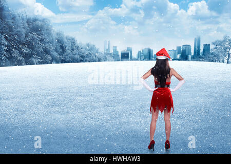 Vue arrière de jeune femme portant le costume du Père Noël sur le champ d'hiver Banque D'Images