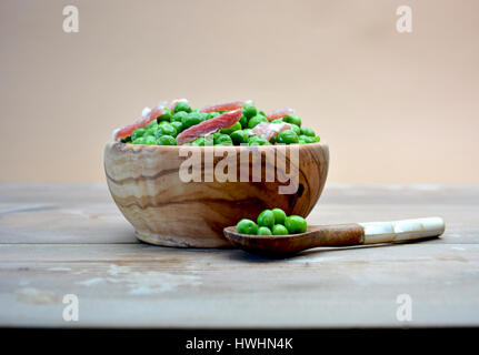 Plat DE BOIS PLEINE DE PETITS POIS AU JAMBON SUR LA TABLE RUSTIC Banque D'Images