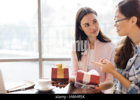 Young businesswoman holding deux cadeaux pendant que son collègue, choisissez-en un Banque D'Images