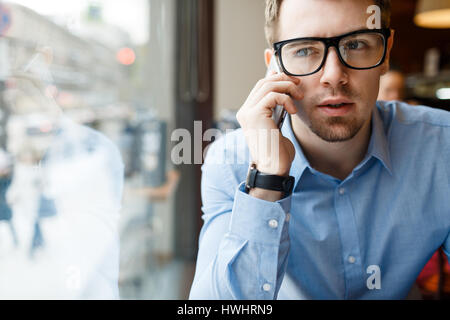 Jeune homme à lunettes et soirée talking on cellphone Banque D'Images