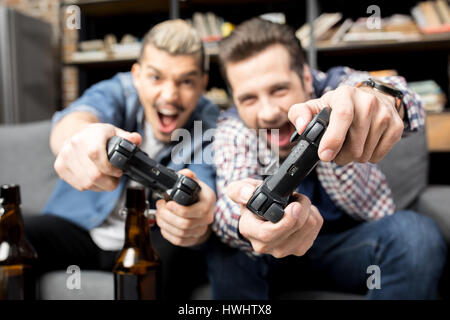 Vue rapprochée de jeunes hommes émotionnelle jouant avec une manette sur la table Banque D'Images