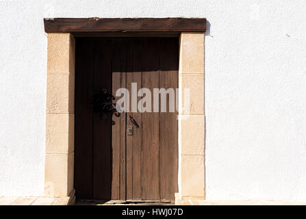 Vieille porte en bois dans un mur blanc avec pierres marron clair autour. côte méditerranéenne, l'Espagne, Moraira Banque D'Images