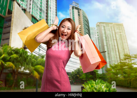Portrait of asian woman holding dans ses mains beaucoup de panier sur l'extérieur de l'arrière-plan centre commercial Banque D'Images