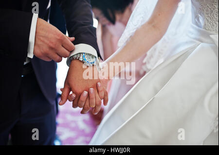 Main dans la main du marié et mariée à l'église cérémonie. Banque D'Images