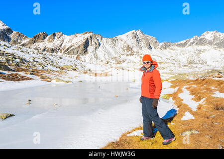 Jeune femme debout près de touristique lac alpin dans Hinczowa valley and smiling to camera, Tatras, Slovaquie Banque D'Images