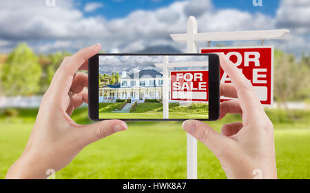 Femme Hands Holding Smart Phone Afficher Photo de Achat Immobilier signe et maison derrière. Banque D'Images