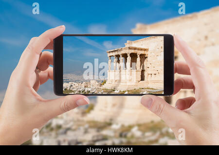 Femme Hands Holding Smart Phone Afficher Photo de cariatides à l'Erechtheum de Acropole d'Athènes, Grèce derrière. Banque D'Images