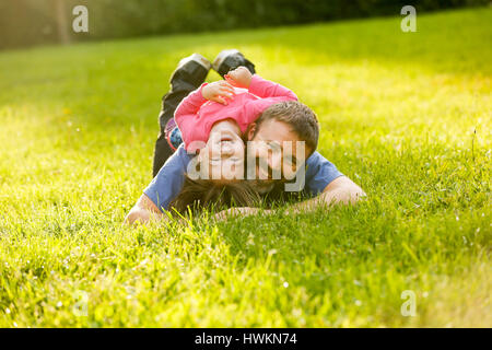 Père dévoué et sa fille couchée sur l'herbe, profitant de chaque compagnie d'autres, le collage, jouer, s'amuser dans la nature sur une journée ensoleillée. La parentalité, l Banque D'Images