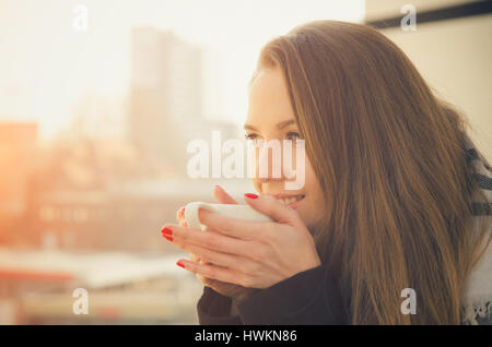 Femme de boire du café ou du thé avec une tasse de café sur le balcon. femme heureuse soleil thé du matin la vie belle notion Banque D'Images