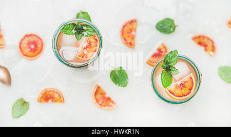 Orange sanguine limonade estivaux, avec de la glace et la menthe dans les verres, gris clair en arrière-plan, selective focus, vue du dessus Banque D'Images