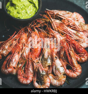 Crevettes rouges grillés avec sauce guacamole avocat en plaque noire Banque D'Images