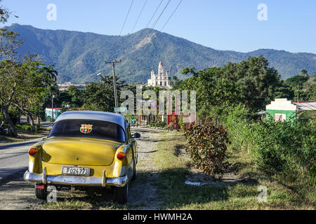 Trinidad, Cuba - 12 janvier 2016 : La route de la Basilique Sanctuaire Maria la Virgen de la Caridad del Cobre. Au premier plan, tenant un vieux American Banque D'Images