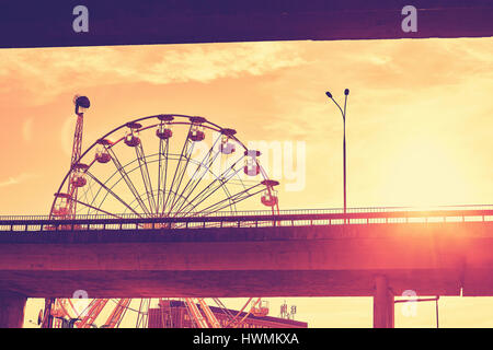 Les tons de couleur photo d'une grande roue contre le coucher du soleil avec effet lens flare. Banque D'Images