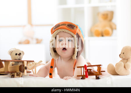 Funny baby boy portée avec chapeau pilote avion en bois et d'ours en peluche jouets Banque D'Images