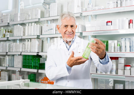 Confiant Pharmacist Smiling en maintenant le produit en pharmacie Banque D'Images