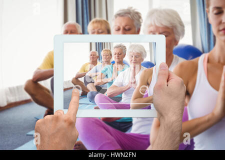 Hand holding tablet pc contre l'opinion des personnes âgées avant de vous détendre avec instructeur de conditionnement physique Banque D'Images