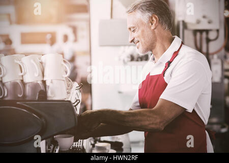 Flare contre l'aide de machine à café barista heureux Banque D'Images