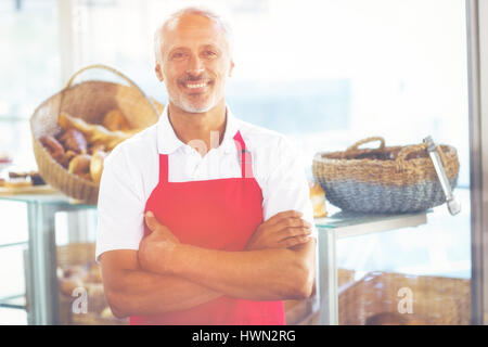 L'image graphique de flare contre barista smiling at camera with arms crossed Banque D'Images