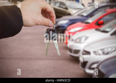 Woman smiling lors de la réception des clés de voiture contre les voitures garées Banque D'Images