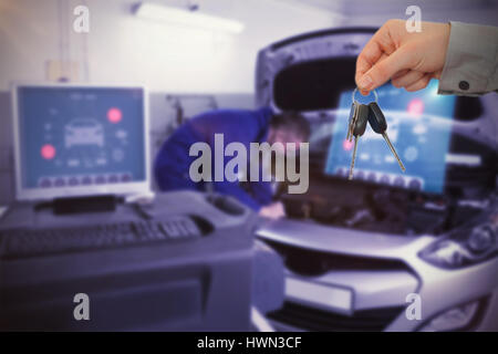 Les clés à quelqu'un homme donnant à l'examen de mécanicien contre moteur de voiture au garage Banque D'Images