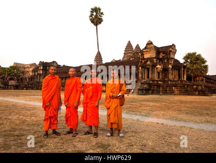Quatre moines bouddhistes en robe orange posent devant Angkor Wat Banque D'Images