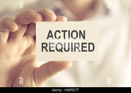 Gros plan sur businessman holding une carte avec texte ACTION REQUISE, concept d'image avec arrière-plan flou et vintage tone Banque D'Images