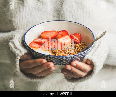 Petit-déjeuner sain yaourt, céréales, bol de fraises dans les mains d'une femme Banque D'Images