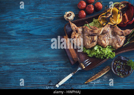 Cailles grillées avec des légumes de la viande sur un fond de bois bleu Banque D'Images