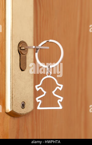 Porte-clés avec une forme féminine dans la serrure d'une porte d'entrée Banque D'Images